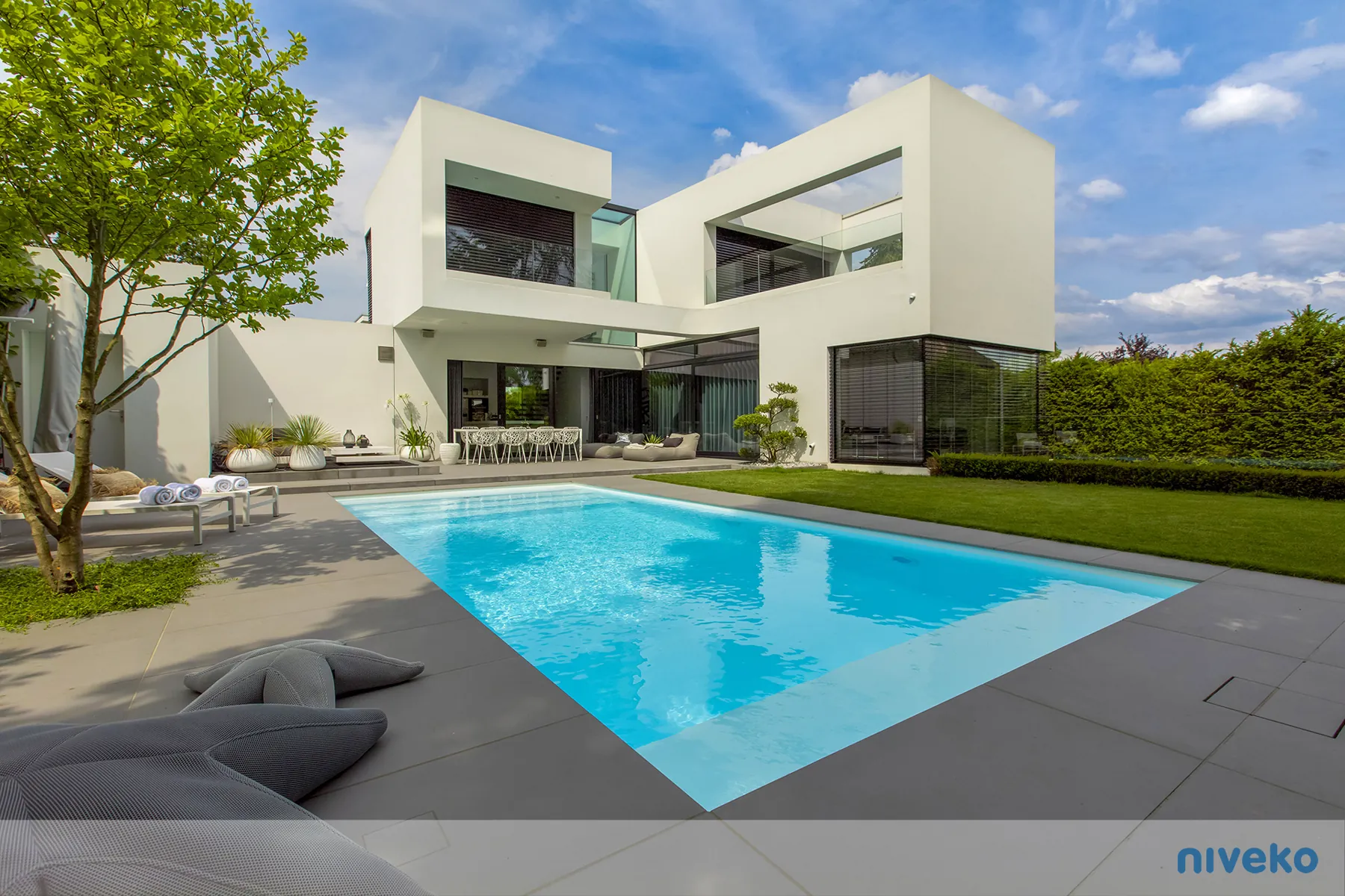 NIVEKO skimmerzwembad met licht terras bij een moderne witte villa